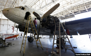 Photo from Santa Maria Times: Former Righetti High School teacher Hector Camacho works to remove a panel from a Douglas C-47 WWII plane at ArtCraft Paint at the Santa Maria Public Airport. 