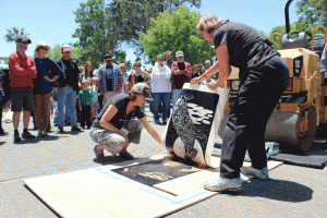 Paso ARTSFEST volunteers pull up a print that was made using a steamroller.