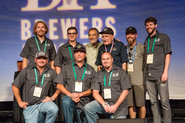 Photo by John Holzer.  Back row, left to right: Patrick Hayes, brewer, Atascadero ; Robert Emery, sensory analyst lab technician, Atascadero; Charlie Papazian of the Brewers Association; Grandpa Brynildson, Minnesota; Matt Brynildson, brewmaster, Paso Robles; Tim Miller, brewer, SLO. Bottom row, left to right:  Ryan Hamill, Brewer, Grover Beach; Dustin Kral, head brewer, SLO; Jason Pond, cellar manager, Atascadero.