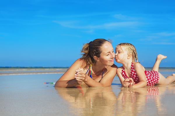 Cute Girl Kissing Happy Smiling Mother On Sea Beach