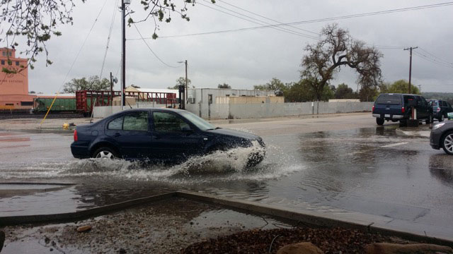 A car splashes through standing water on Pine Street at 5th Street on Friday.