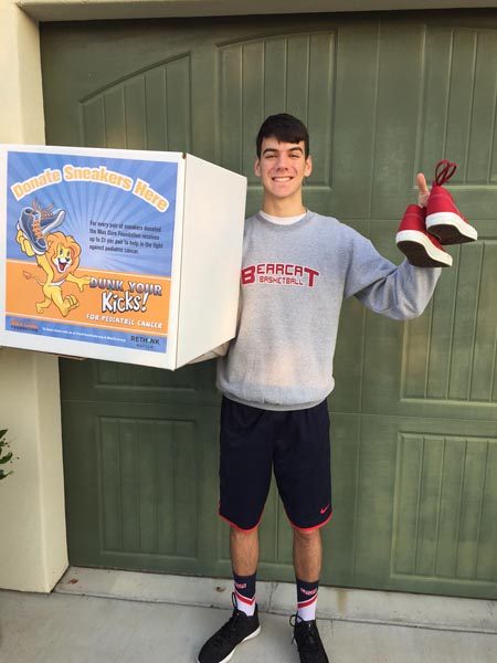 Dante Coletta holding one of the collection boxes for Dunk Your Kicks fundraiser.