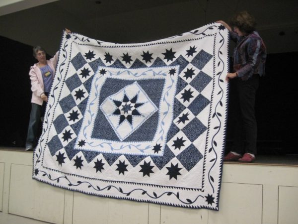 Almond Country Quilt Guild members displaying a quilt.