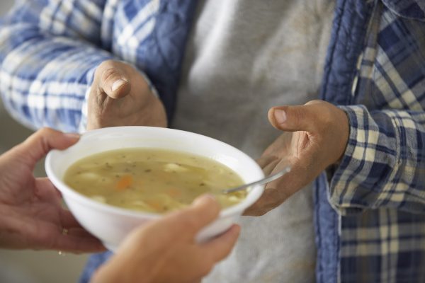 Woman giving bowl of soup to man
