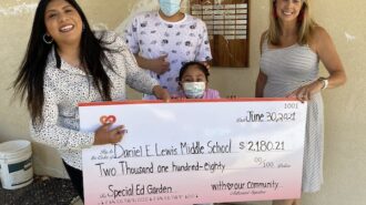 School administrators accept check to cover damage done to middle school garden