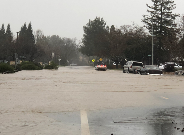A car drives though more than a foot of water on Scott Street in Paso Robles.